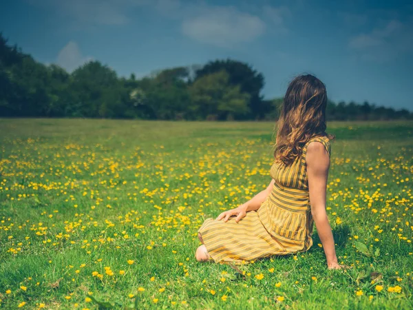 Μια Νεαρή Γυναίκα Που Φοράει Ένα Φόρεμα Κάθεται Μεταξύ Buttercups — Φωτογραφία Αρχείου