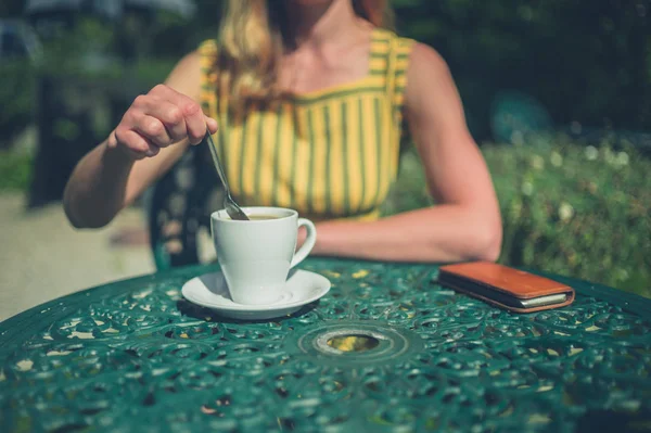 女性はカフェの庭で彼女のコーヒーをかき混ぜながら — ストック写真