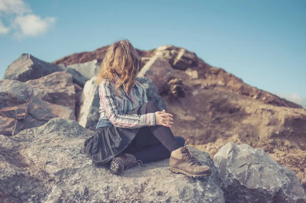 一个年轻的女人正坐着石头 — 图库照片