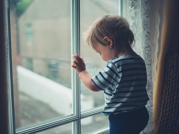 Маленький Хлопчик Стоїть Біля Вікна Дивлячись Похмурий День — стокове фото