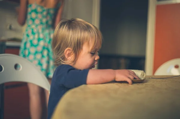 Ett Litet Småbarn Sitter Köket Med Sin Mamma Matlagning Bakgrunden — Stockfoto