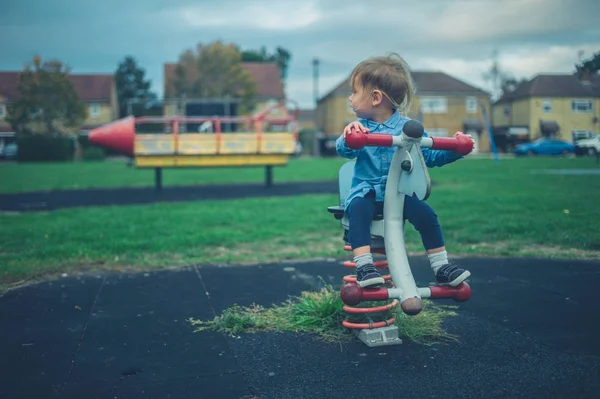 小さな幼児は遊び場の遊具に座っています — ストック写真