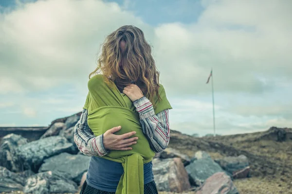 Genç Bir Anne Bebeğini Bir Askı Içinde Arka Planda Amerikan — Stok fotoğraf