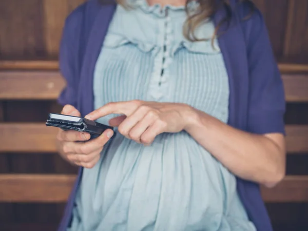 Een Zwangere Vrouw Het Gebruik Van Een Smartphone Een Houten — Stockfoto