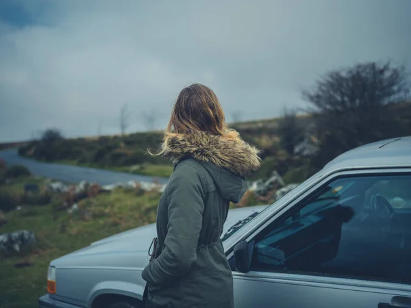 秋の湿原に彼女の車で若い女性が立っています — ストック写真