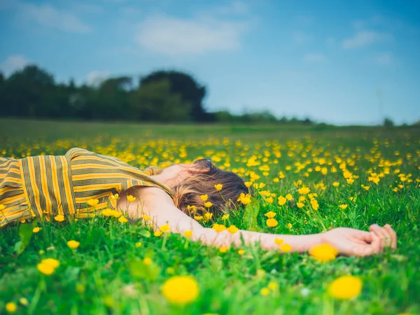 一个年轻的女人躺在草地上 周围都是蝴蝶 — 图库照片