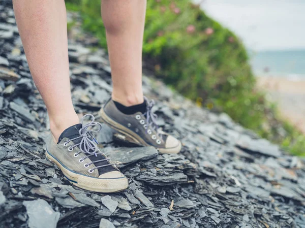 一个年轻女子站在海岸附近的一些石头上的脚 — 图库照片