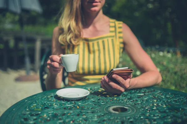 A young woman is drinking coffee outside in a garden in the summer