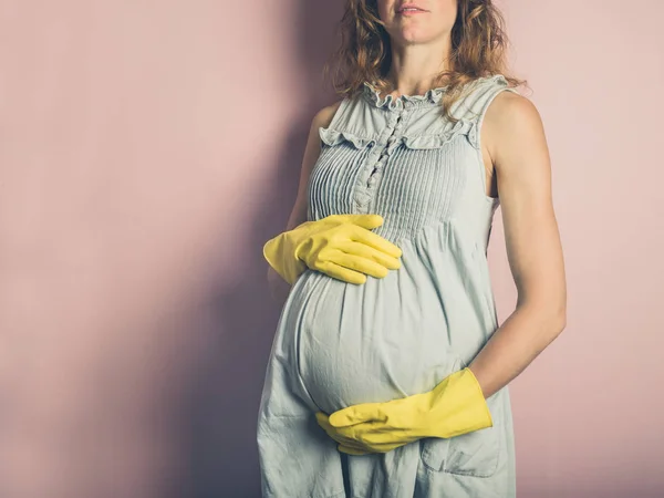 一名年轻孕妇戴着黄色橡胶手套 — 图库照片