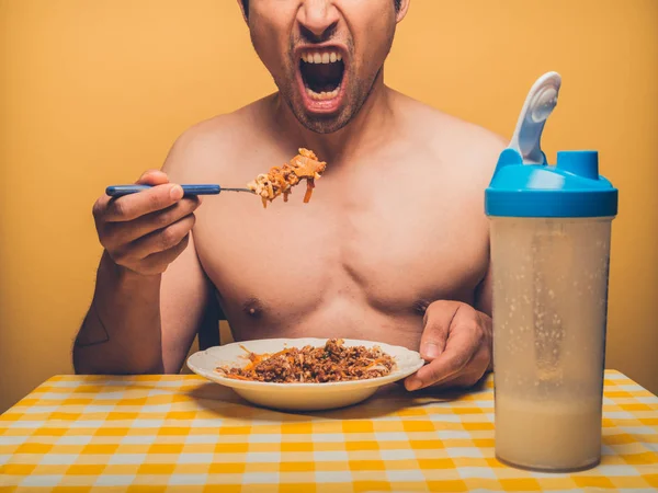 Ein Junger Fitnessmann Vor Gelbem Hintergrund Isst Hackfleisch Und Proteinshake — Stockfoto