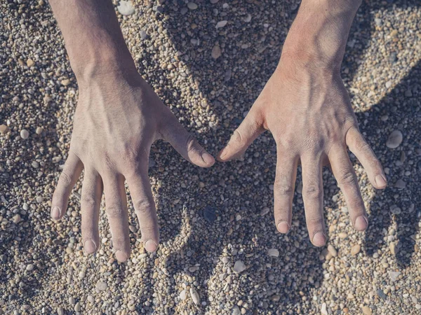 cropped image of male hands in mud