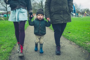 Annesi ve büyükannesi ile küçük bir toddler açık havada bir parkta yürüyor