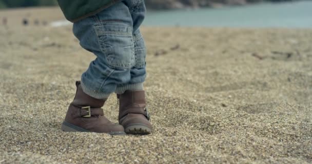 一个小男孩穿着靴子走在海滩上 慢动作手持式镜头 — 图库视频影像