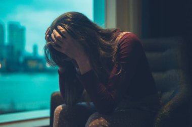 Üzgün bir kadın pencerenin bir şehirde oturuyor