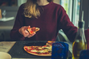 Genç bir kadın bir restoranda pizza yiyor