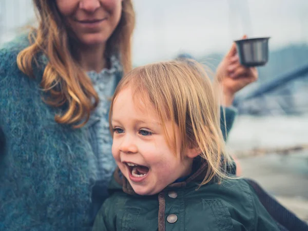 笑う幼児がお茶を飲んでいる母親と屋外です — ストック写真