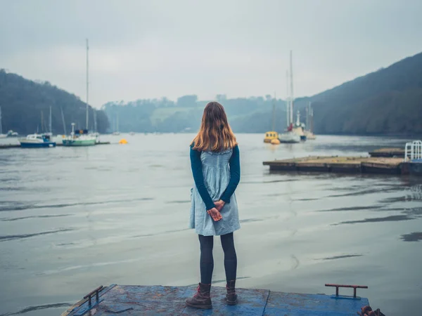 一个年轻的女人站在锈迹斑斑的老码头上 — 图库照片