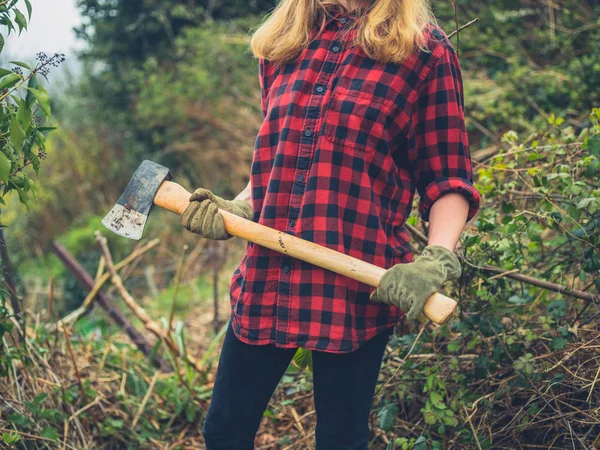 Mujer joven en el jardín con un hacha — Foto de Stock