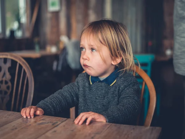 Küçük bir çocuk bir kafede bir masada oturuyor