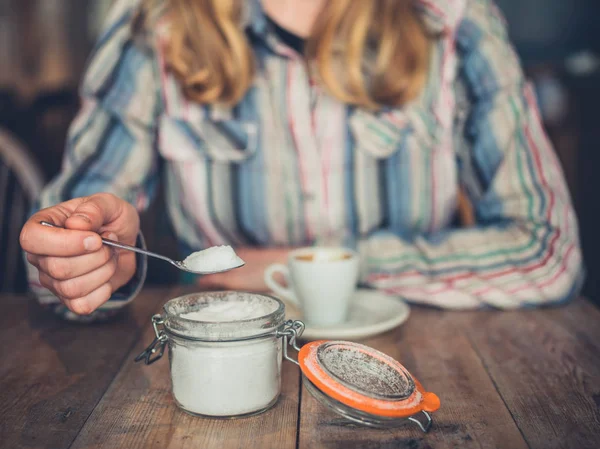 カフェの若い女性がコーヒーに砂糖を加えています — ストック写真