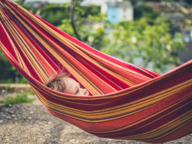 Küçük bir bebek bir hamakta rahatlıyor.