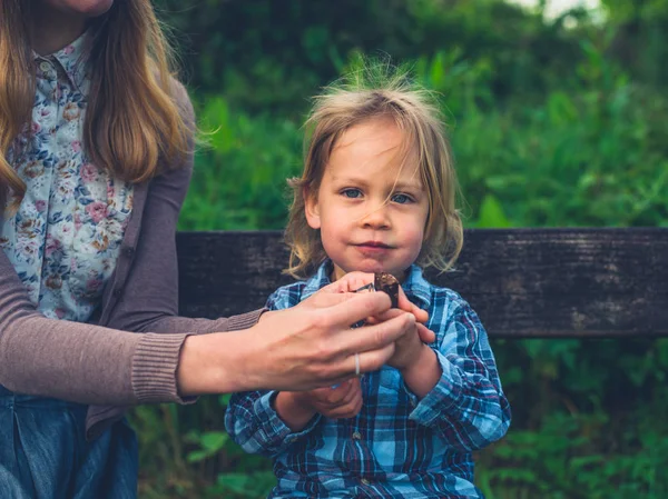 Una Joven Madre Está Dando Hijo Una Barra Fruta Banco — Foto de Stock