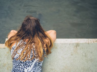 Genç bir kadın nehir de yatıyor ve suya bakıyor.