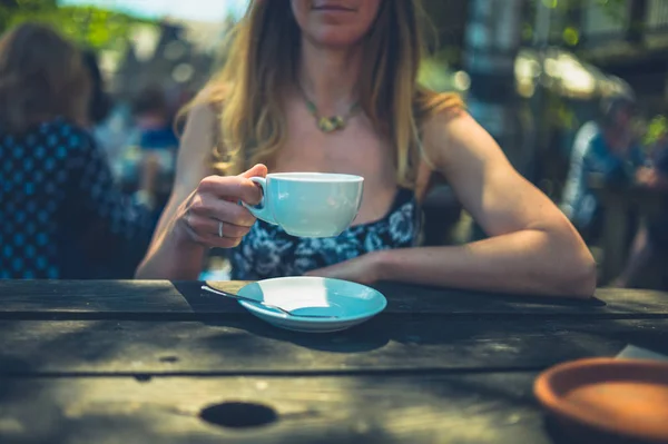 一位年轻女子在户外的咖啡馆喝咖啡 — 图库照片
