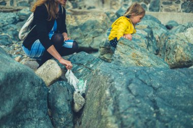 Yaz aylarında plajda plastik atık temizleme Genç Anne ve küçük Toddler