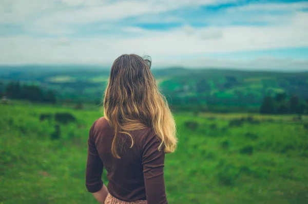 夏の丘と緑の風景を見る若い女性の背面図 — ストック写真