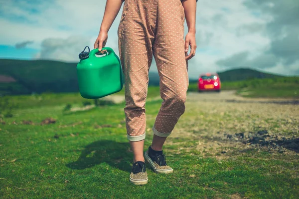 一个年轻女子正拿着一罐汽油在荒野中行走 — 图库照片