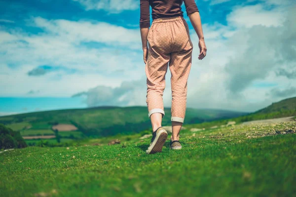 若い女性が晴れた夏の日に荒野を歩いている — ストック写真