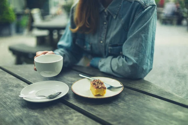 若い女性がコーヒーを飲み 自然の中でケーキを食べている — ストック写真