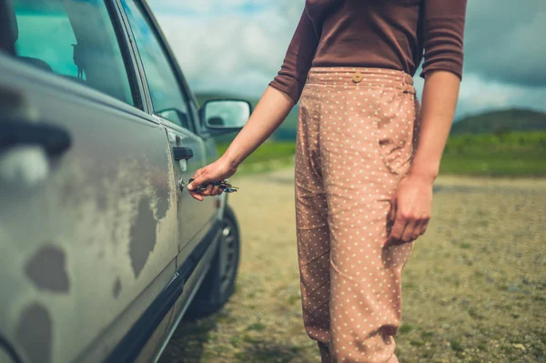 若い女性は 夏の日に自然の中で彼女の車のロックを解除しています — ストック写真