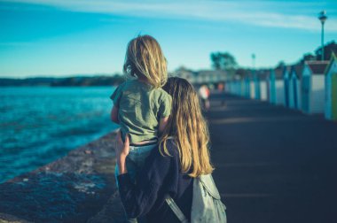 Genç bir anne, çocuğunu denizden kaldırıyor.