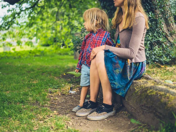 Genç bir anne ve onun yürümeye başlayan çocuk parkta bir günlük üzerinde rahatlatıcı