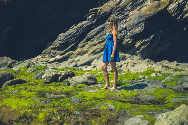 若い女性が夏に岩のビーチに立っている — ストック写真