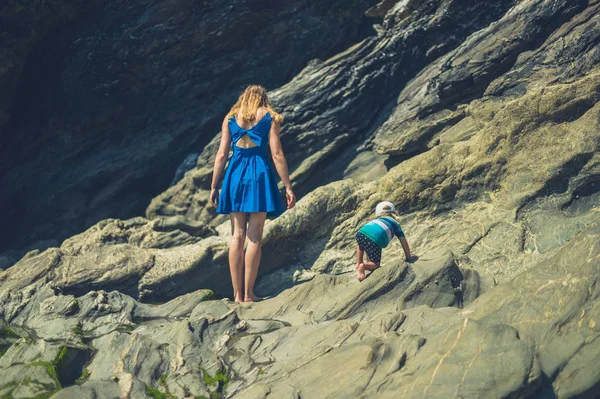 一位年轻的母亲和她的小孩在岩石海滩上散步 — 图库照片