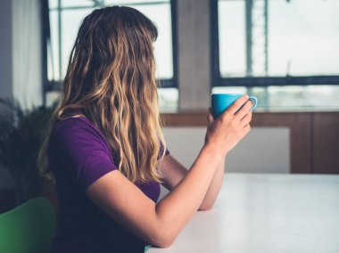 Genç bir kadın bir şehir evinde kahve içiyor