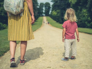 Genç bir anne ve onun bebek bir parkta bir yolda duruyor