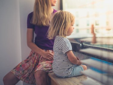 Genç bir anne ve onun küçük yürümeye başlayan bir şehir dairenin penceresinden dışarı bakıyor