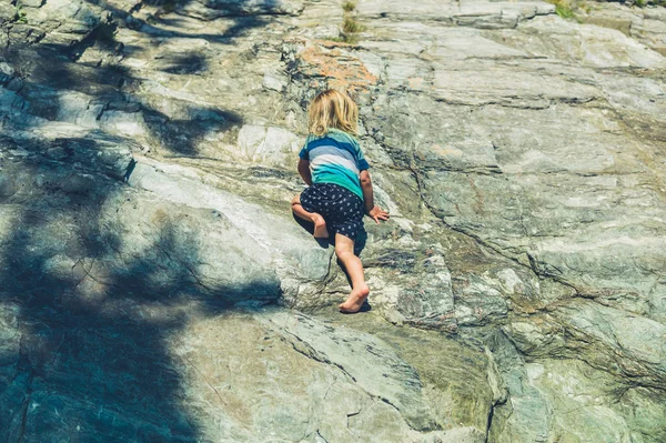 小さな幼児は 夏にいくつかの岩に登っています — ストック写真