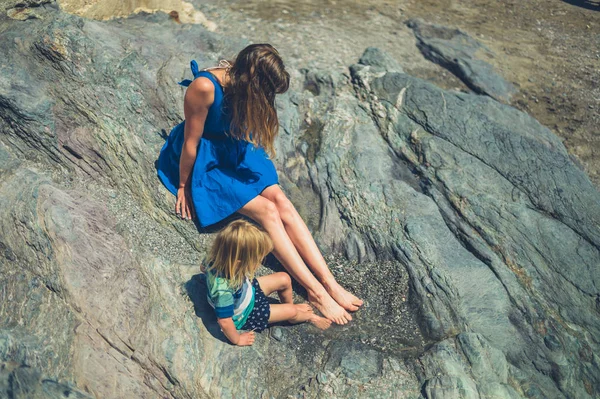 若い母親と彼女の幼児は 夏にいくつかの岩の上に座っています — ストック写真