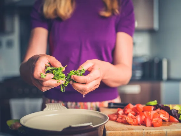 Junge Frau bereitet Salat mit Tomaten und Avocado zu — Stockfoto