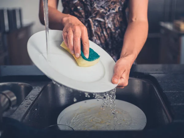 Mujer joven limpiando los platos en su cocina —  Fotos de Stock