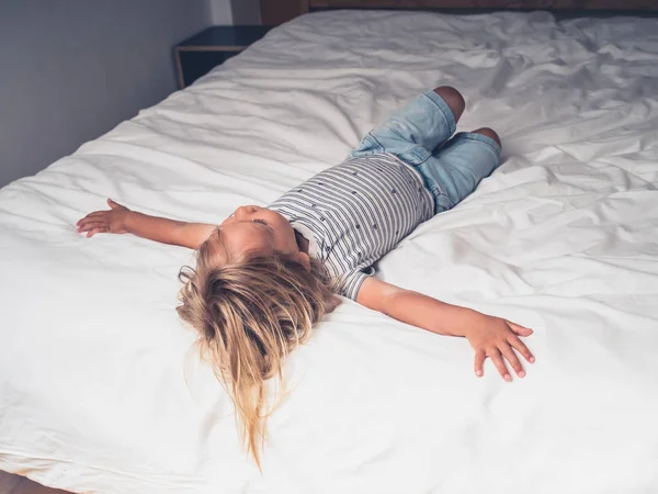 一个蹒跚学步的孩子正在城市公寓的床上放松 — 图库照片
