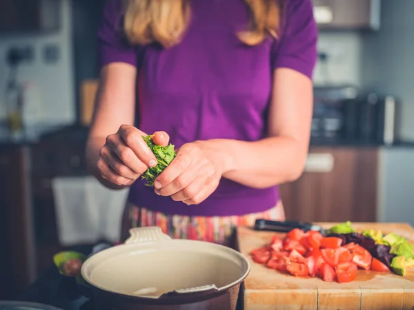 Junge Frau bereitet Salat mit Tomaten und Avocado zu — Stockfoto