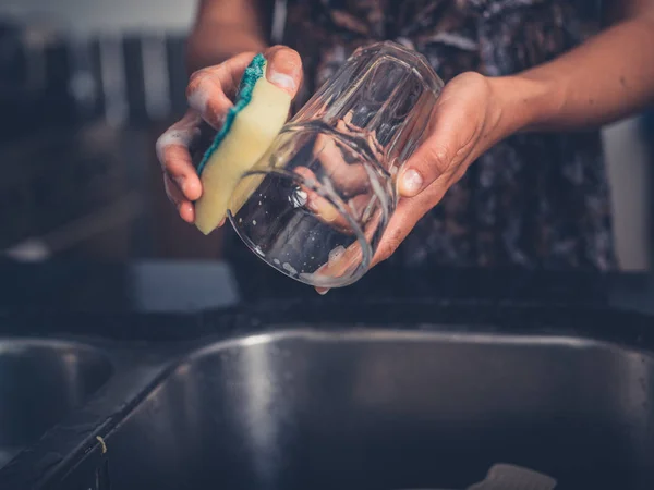 Mladá žena uklízet nádobí v kuchyni — Stock fotografie