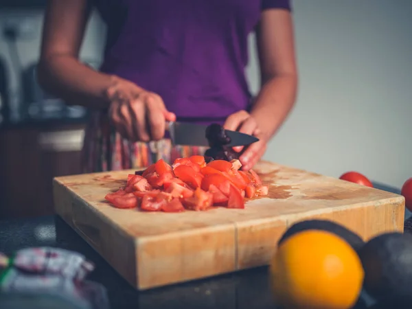 Mujer joven preparando ensalada con tomates y aguacate —  Fotos de Stock