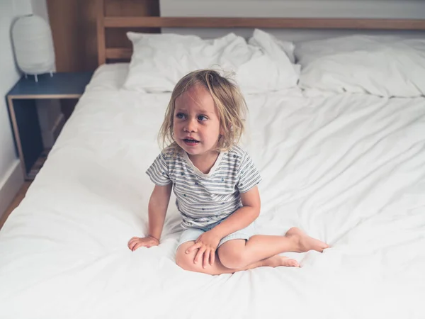 Ένα Μικρό Νήπιο Κάθεται Ένα Κρεβάτι Λευκά Σεντόνια — Φωτογραφία Αρχείου